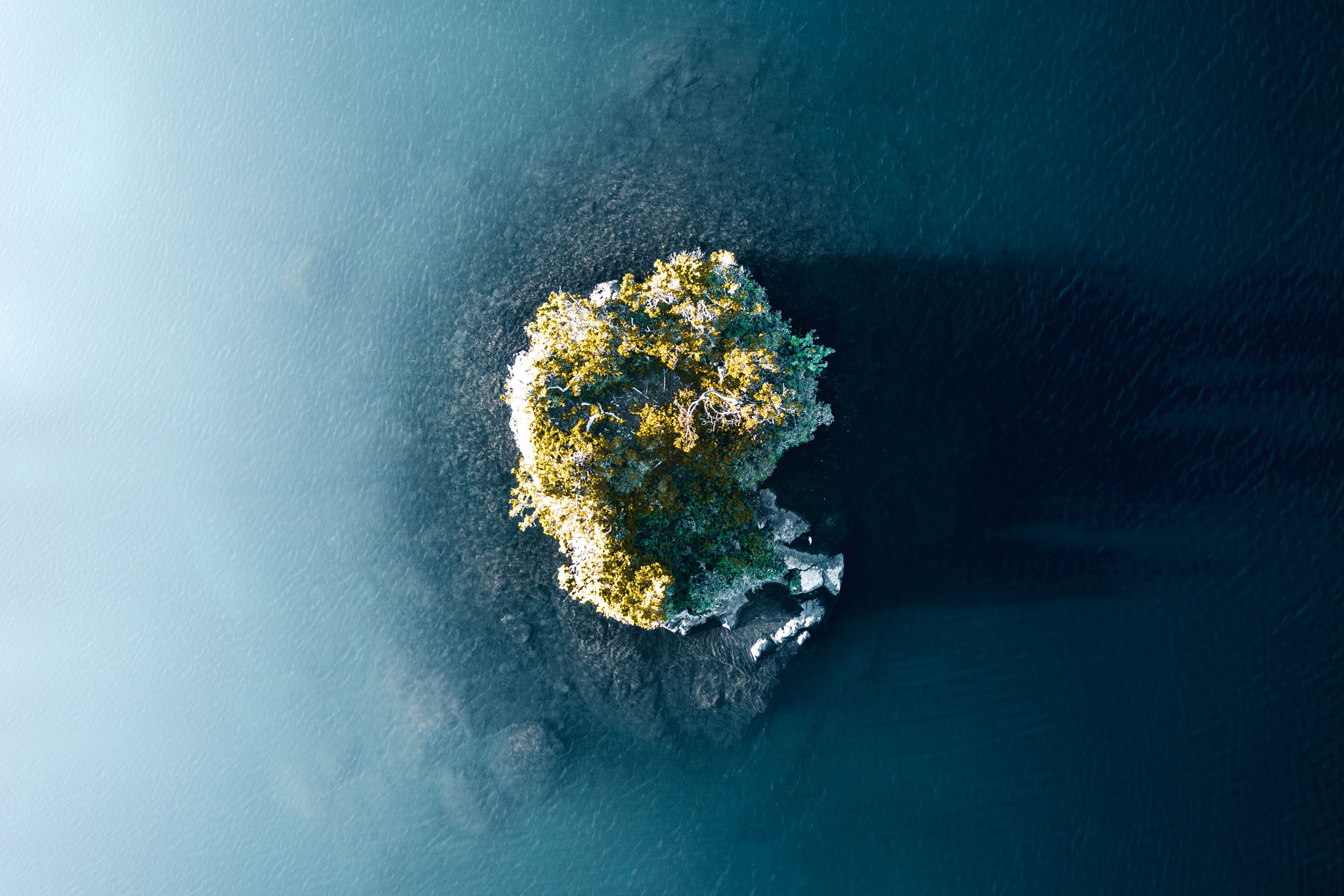 Aerial shot of a small island in the middle of a lake in the French alps.