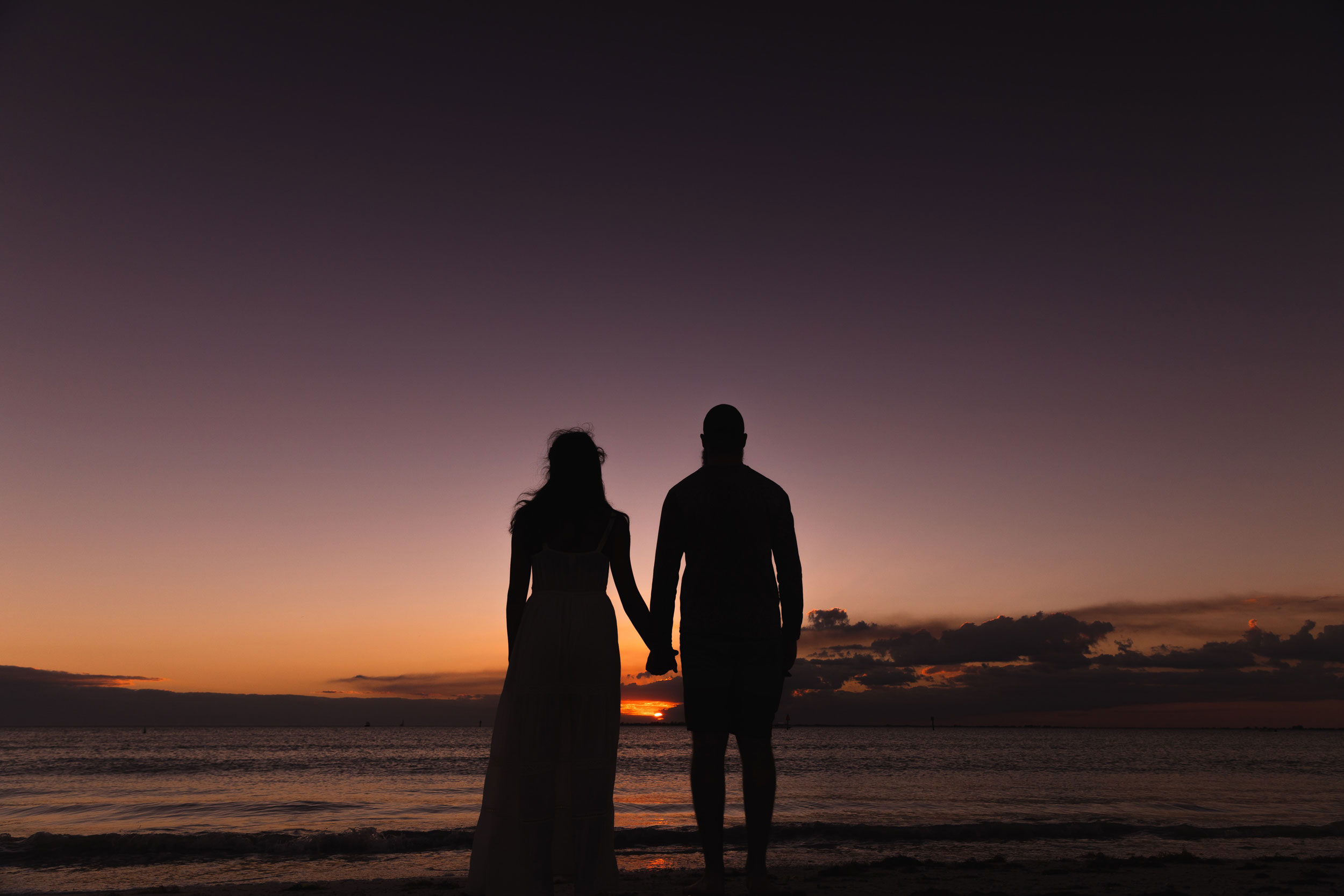 Two people holding hands at sunset.