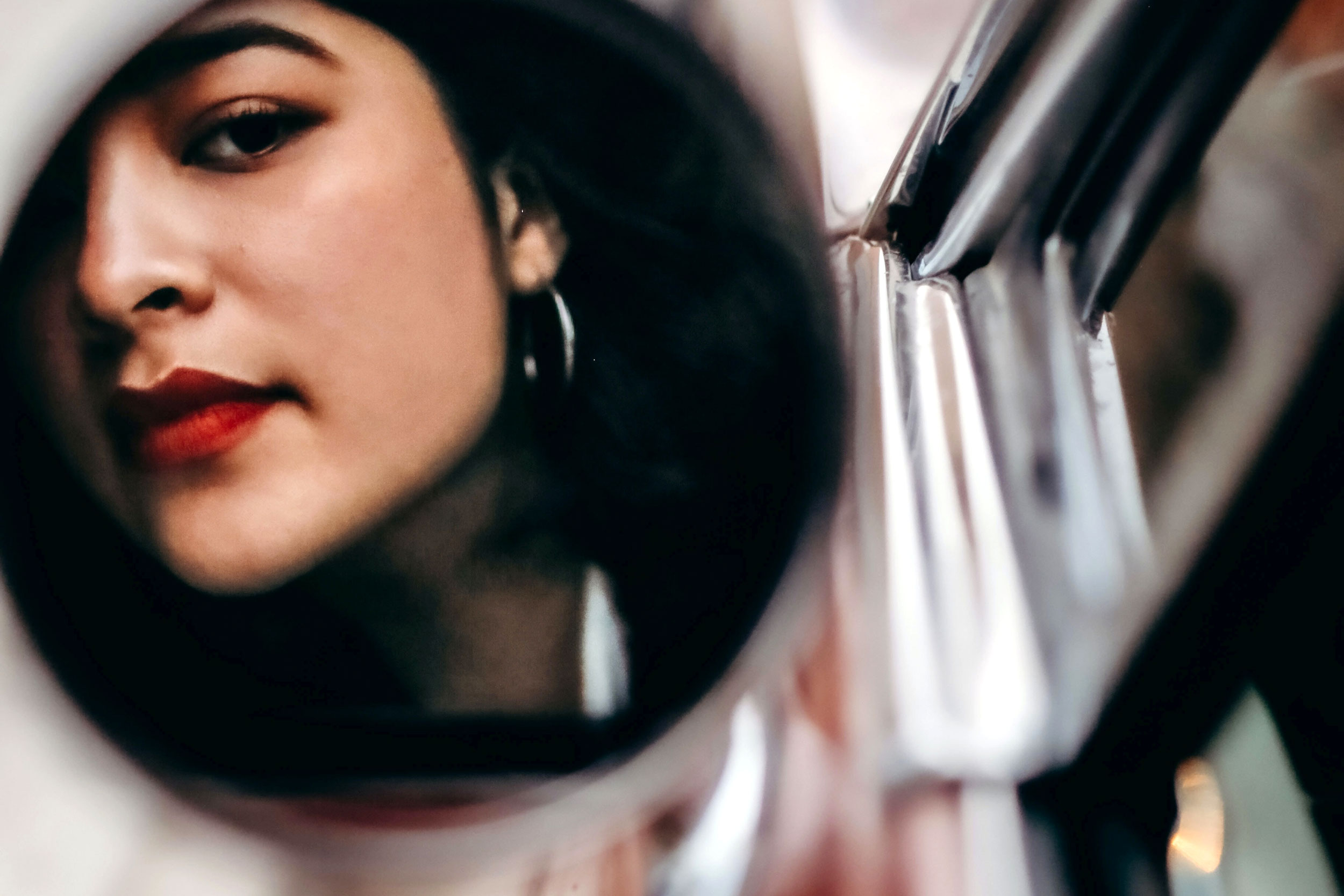 Woman looking in the sideview mirror of a car
