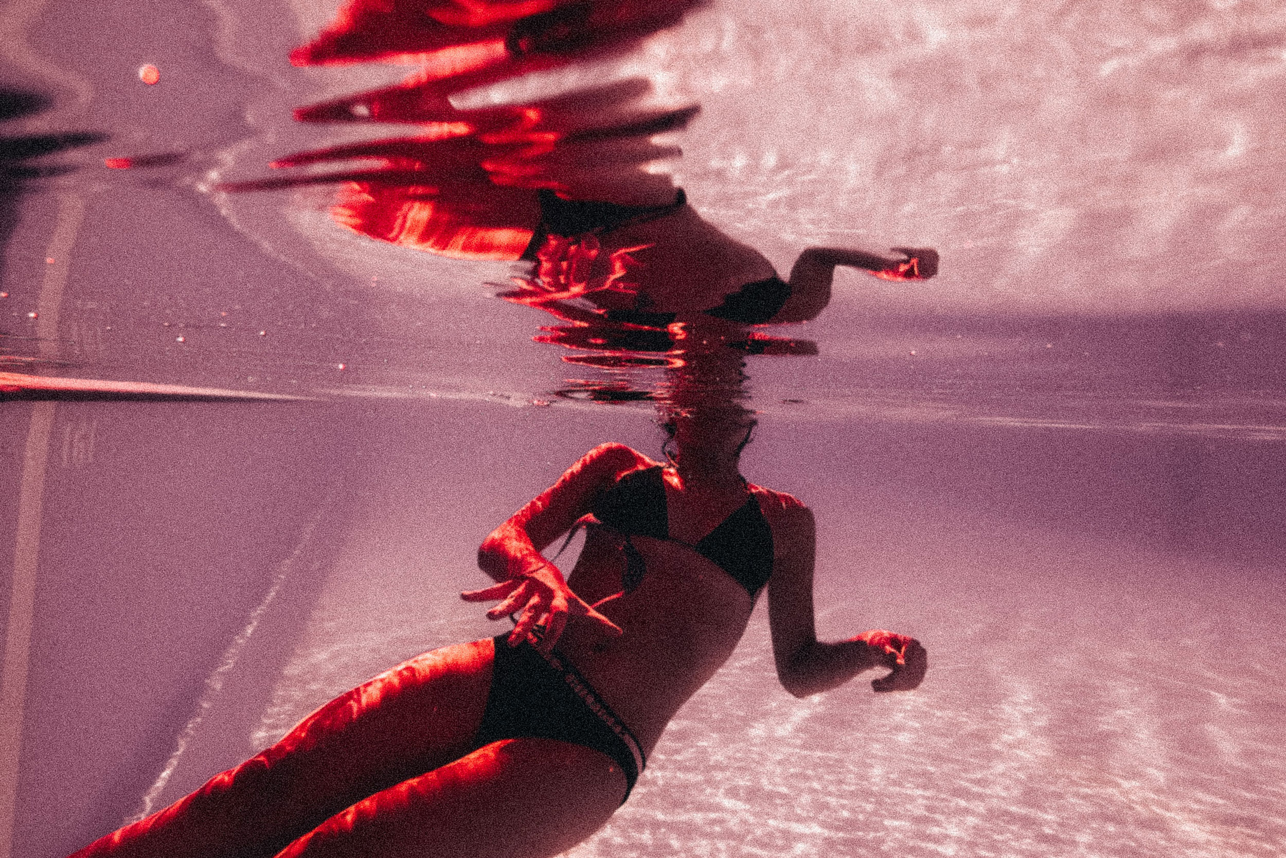 Woman half underwater in swimming pool with distorted reflection
