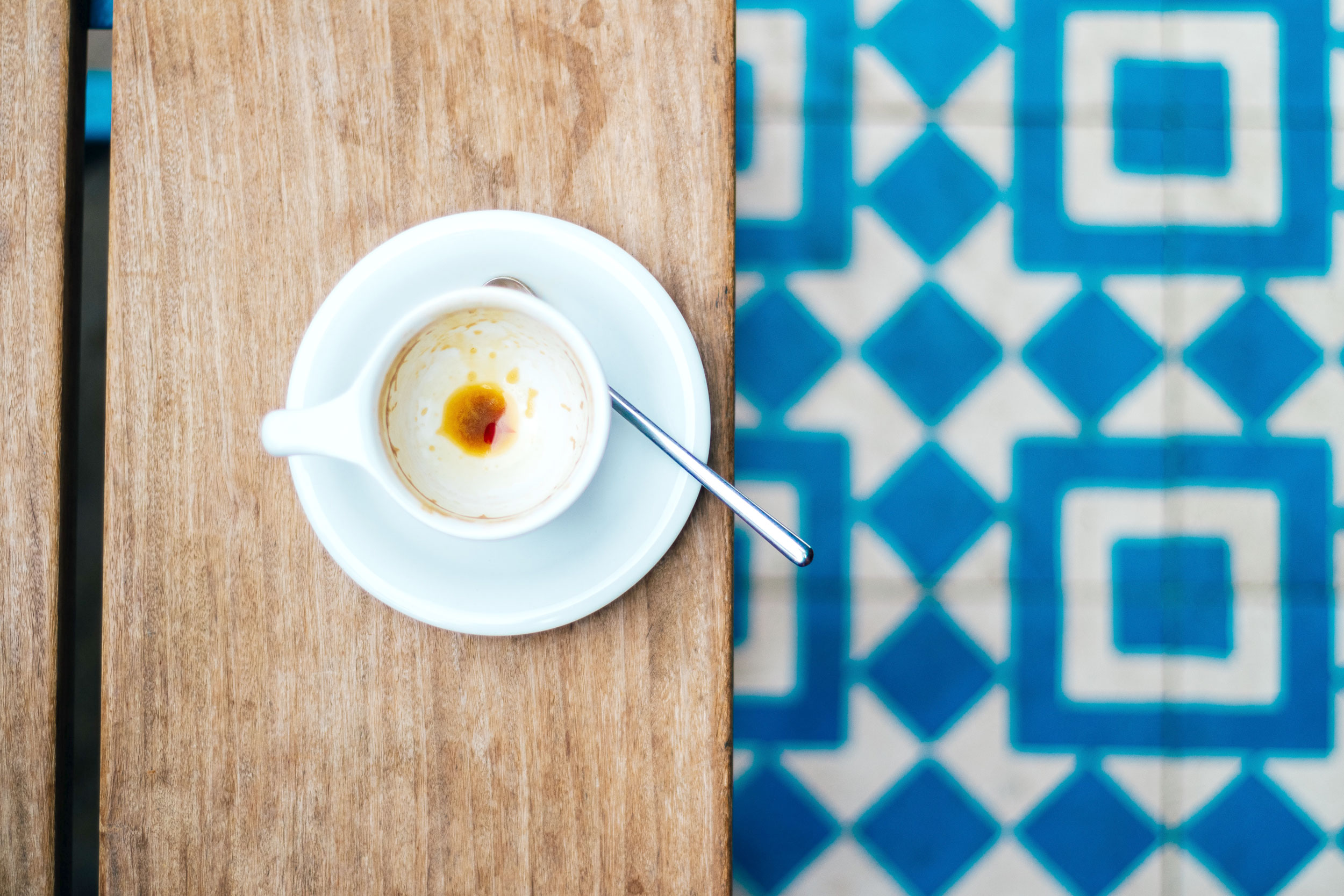 Empty coffee cup against blue tile.