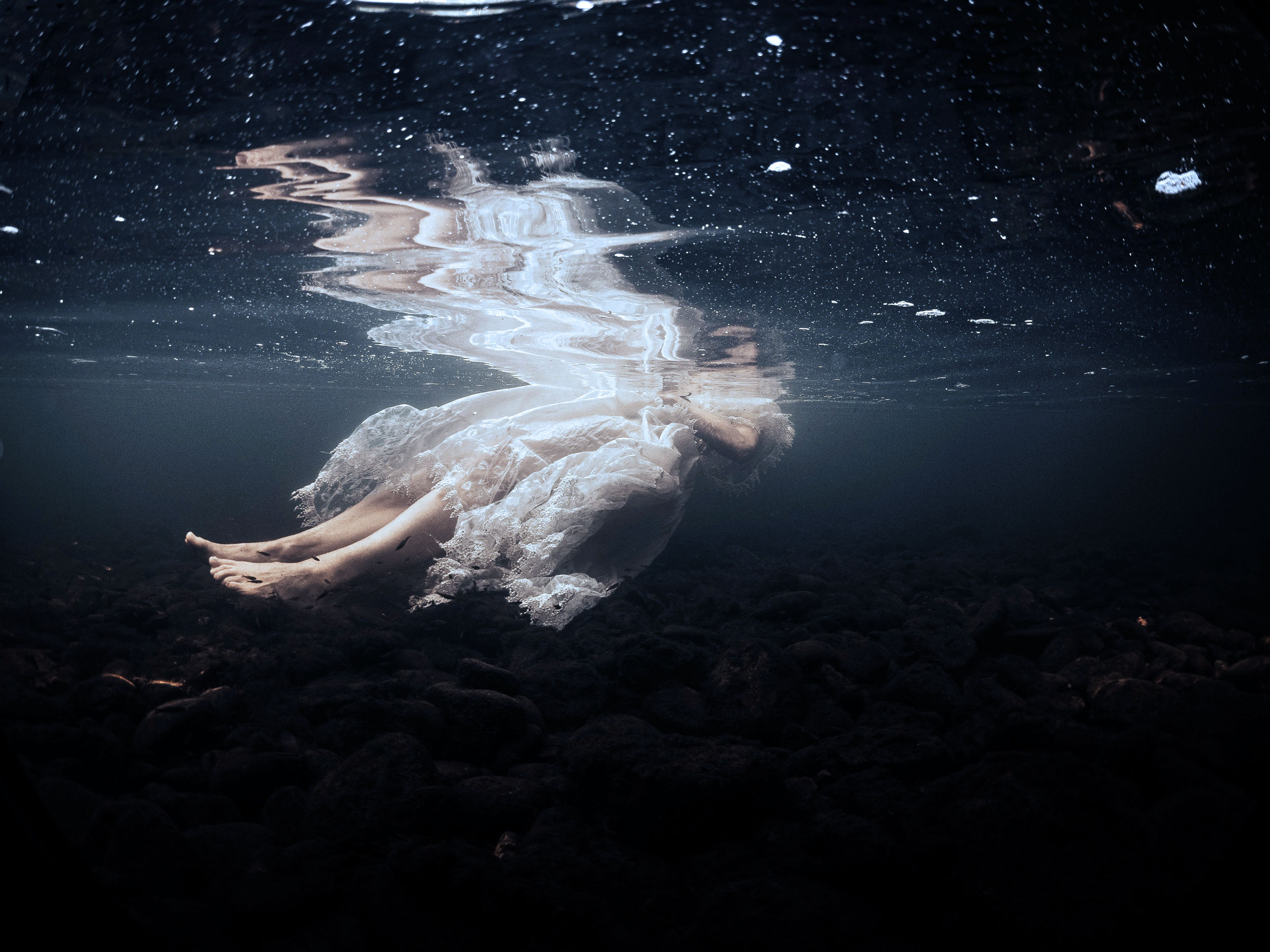 Woman floating underwater in a white dress